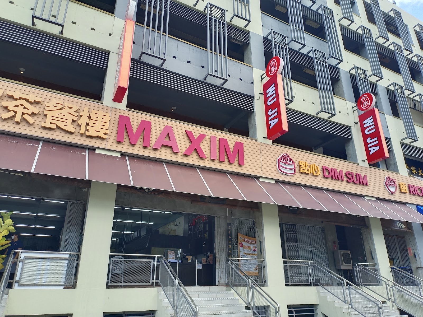Maxim Dim Sum Restaurant shopfront on Lebuh Pekaka 1 — red Maxim signage above 'Dim Sum' and 'Noodle' chops, sky and motorbikes parked outside